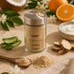 A glass jar of Purfi Skin Brightening Exfoliating Cleanser with a silver lid, styled on a beige fabric background with ingredients like aloe vera, sweet orange, slippery elm bark, coconut milk, and a spoon of the beige powder.